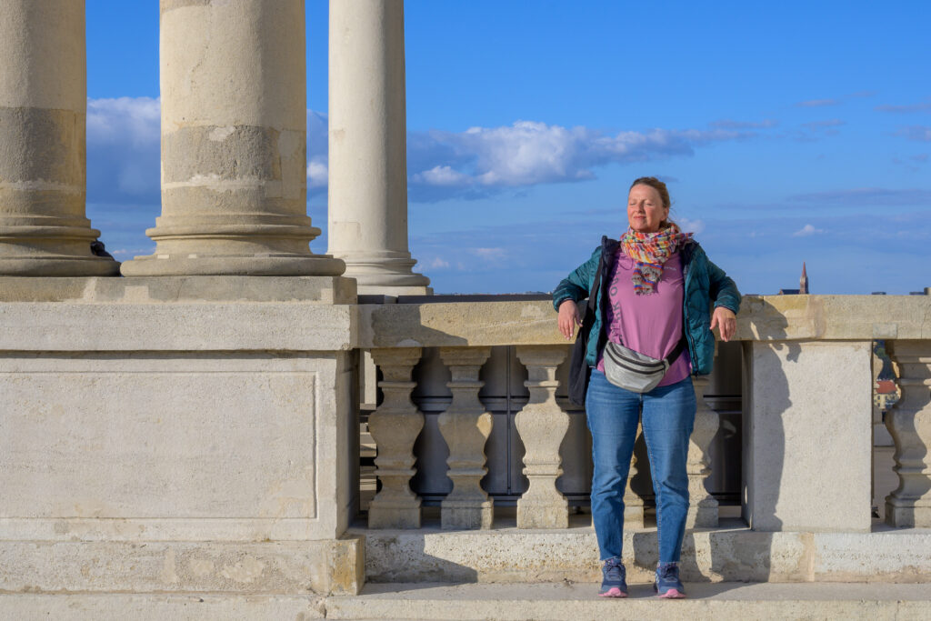 A woman stands next to a monument and catches the afternoon sun.