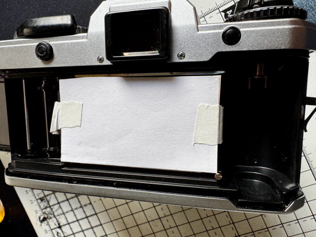 Yashica FX-D film chamber open, with protective card covering the shutter blades.