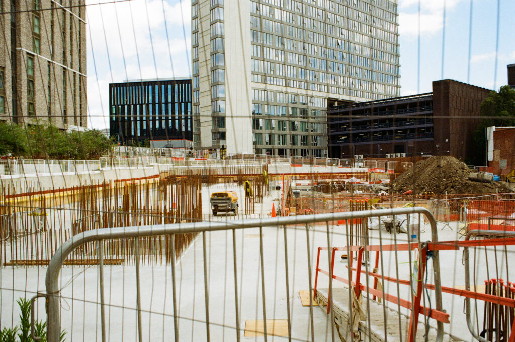 Building a new Sheffield. Reinforcing bars set into lower levels of concrete on a building site, taken through a wire fence.