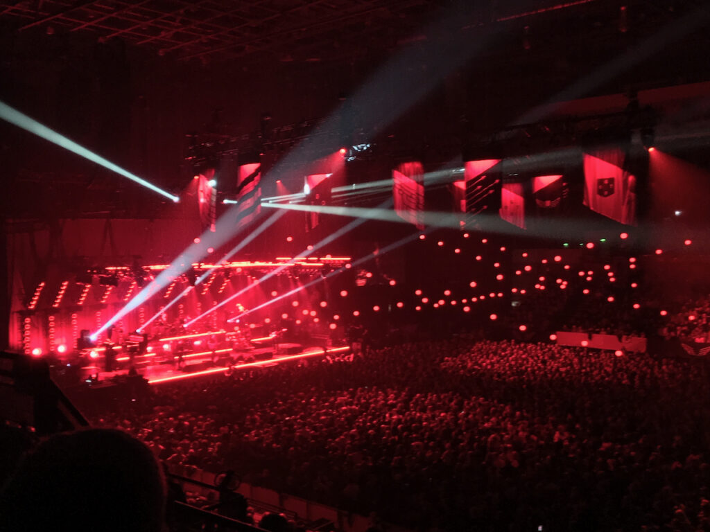Photo from a concert, largely red, with some spotlights