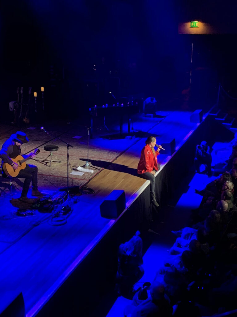 Singer sat on the stage front facing the audience.