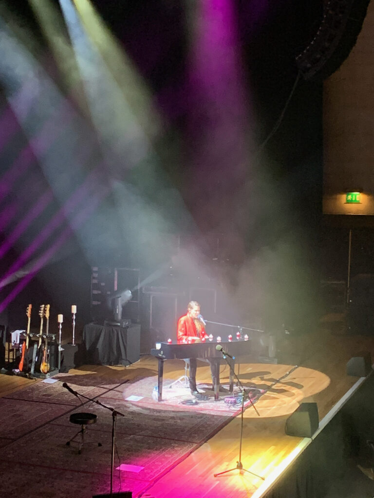 Singer at a piano with spotlights