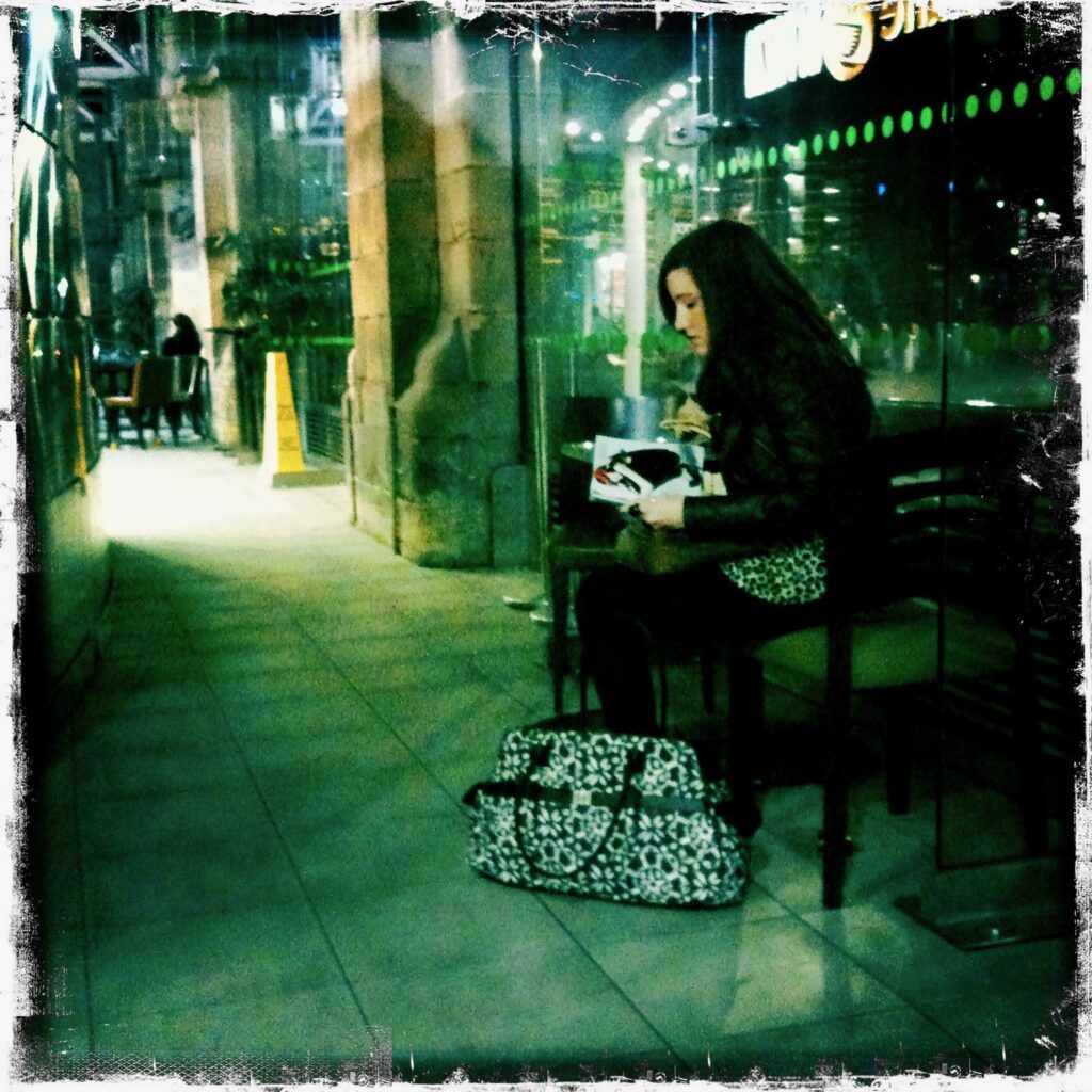 Girl reads a book as she sits waiting for a train