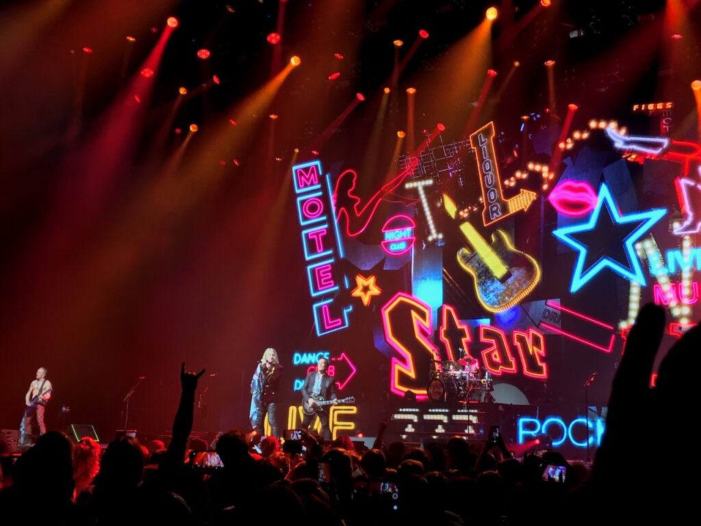 Concert image, lots of neon signs on a back drop