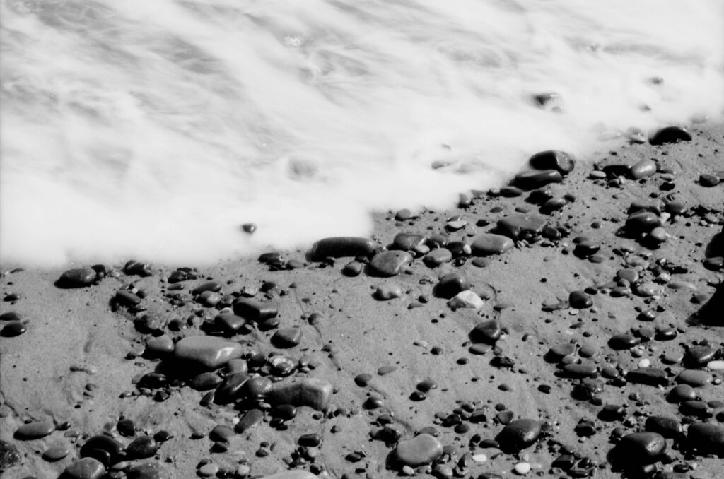 The sea runs over pebbles on a beach.
